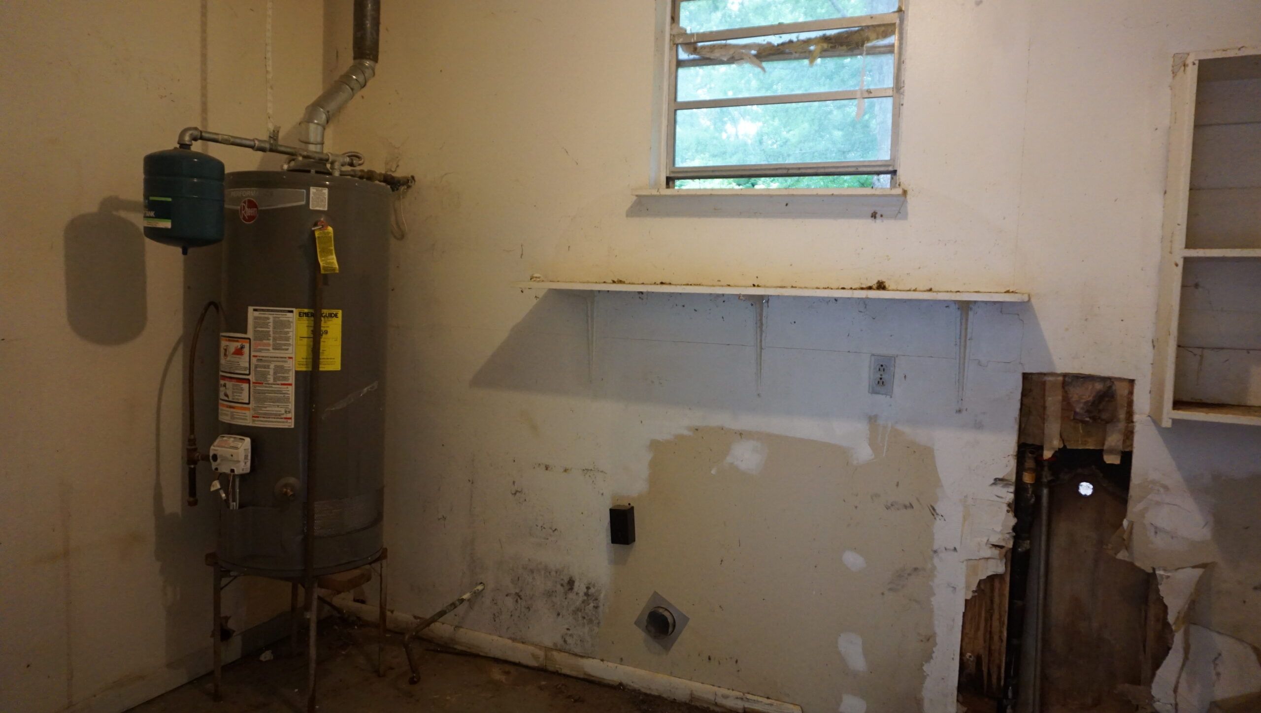 Utility room before renovation Atlanta GA — mold damage, broken window, exposed plumbing