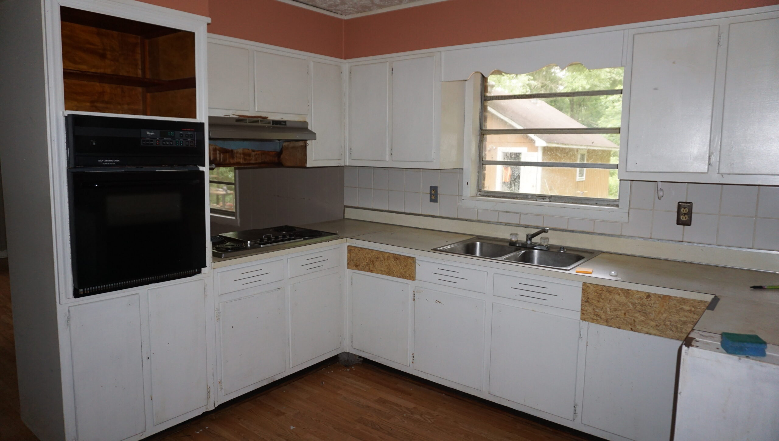 Kitchen before renovation Atlanta GA — dated cabinets, OSB patches, broken window