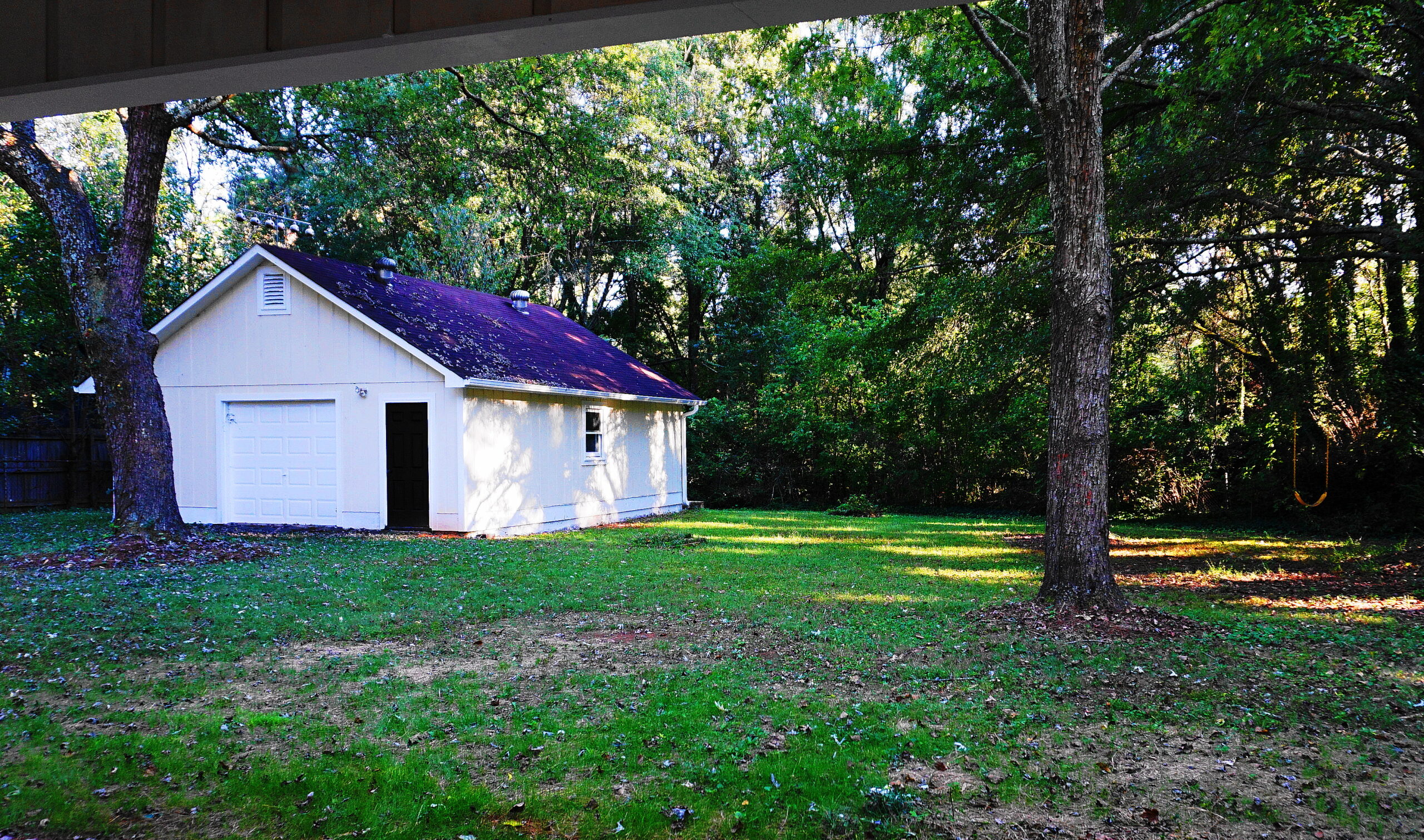 Backyard and outbuilding after renovation Atlanta GA — clean lawn, renovated white outbuilding